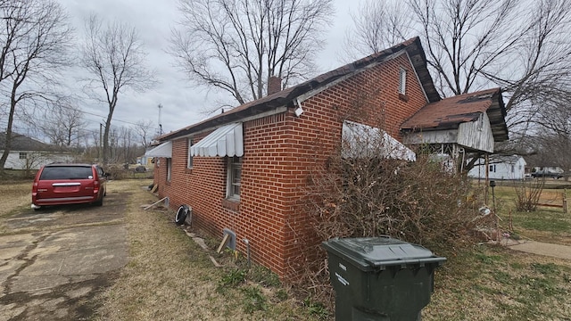 view of home's exterior with a chimney and brick siding