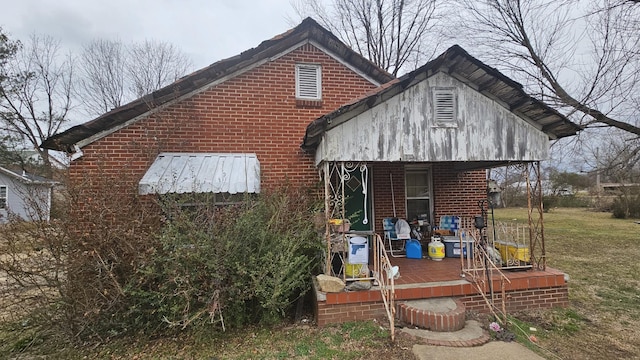 rear view of house with covered porch and brick siding