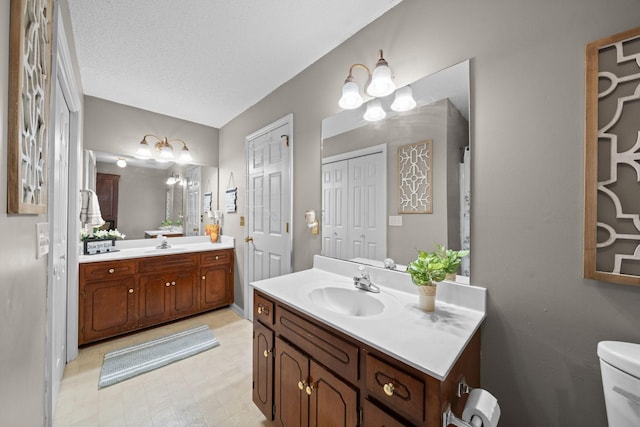 full bath with two vanities, a sink, toilet, and tile patterned floors