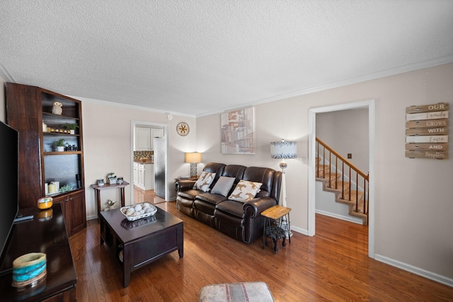 living room featuring baseboards, a textured ceiling, ornamental molding, and wood finished floors