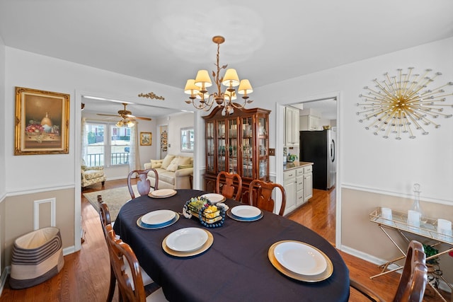 dining space featuring baseboards, light wood-type flooring, and an inviting chandelier