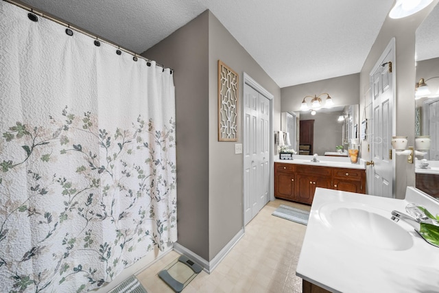 bathroom with a textured ceiling, two vanities, and a sink