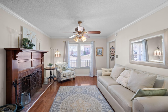 living room featuring ornamental molding, a brick fireplace, a textured ceiling, and wood finished floors