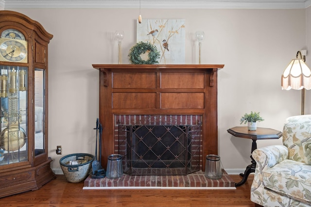 living area featuring a fireplace, crown molding, baseboards, and wood finished floors