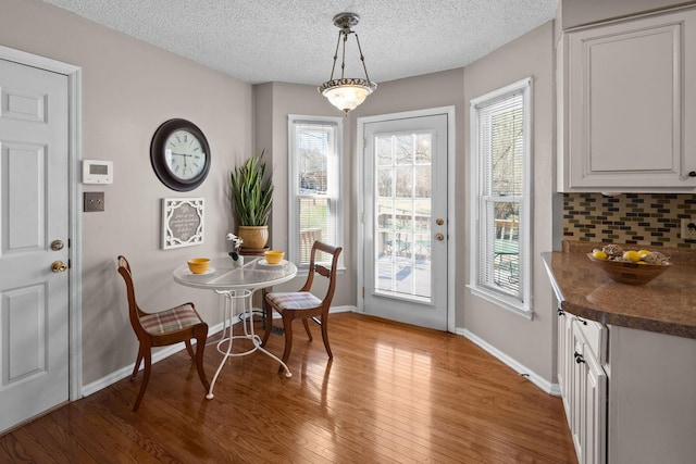 dining area with light wood-style floors, a textured ceiling, and baseboards