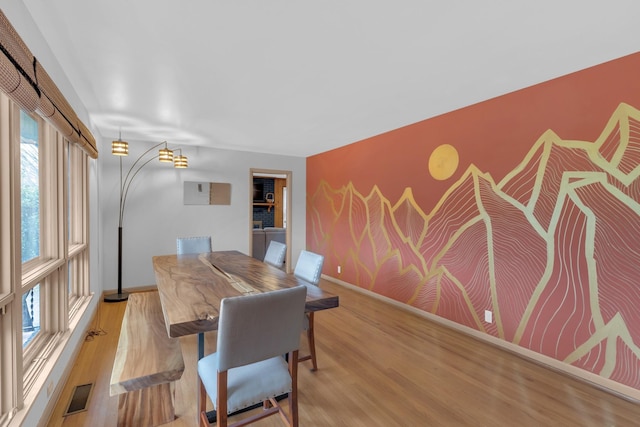 dining space with light wood-style flooring, an accent wall, visible vents, and baseboards