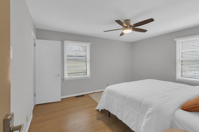 bedroom with light wood-style flooring, multiple windows, visible vents, and baseboards