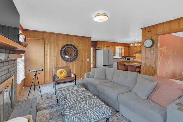 living area with a brick fireplace, wooden walls, and a notable chandelier