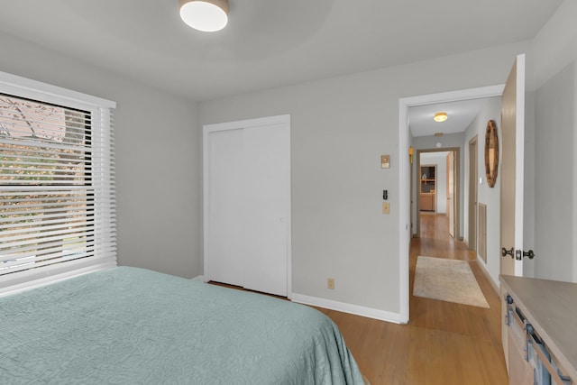 bedroom featuring light wood finished floors, a closet, and baseboards