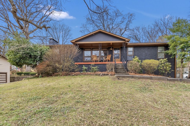 view of front of property with covered porch, brick siding, a chimney, and a front yard