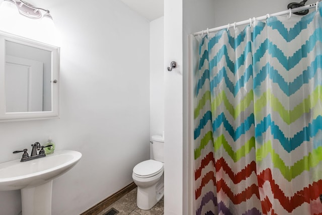 bathroom with toilet, a shower with curtain, a sink, and tile patterned floors