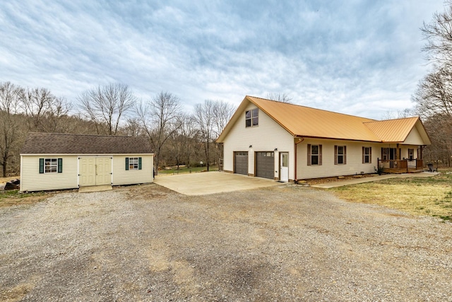 exterior space featuring a garage, covered porch, driveway, and an outdoor structure