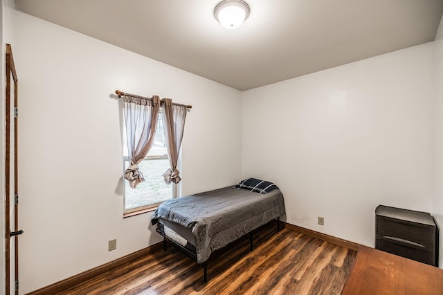 bedroom with dark wood finished floors and baseboards