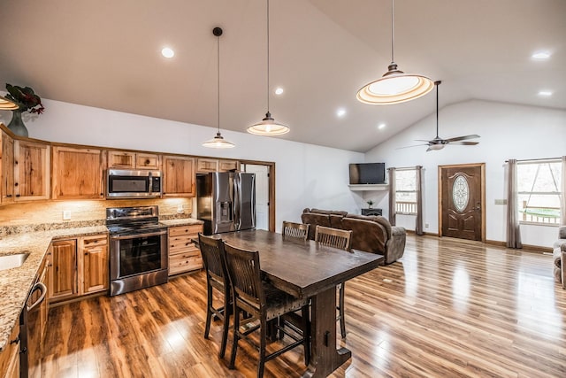 kitchen with stainless steel appliances, wood finished floors, high vaulted ceiling, and tasteful backsplash