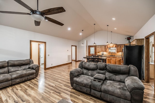 living area featuring light wood finished floors, baseboards, visible vents, ceiling fan, and high vaulted ceiling