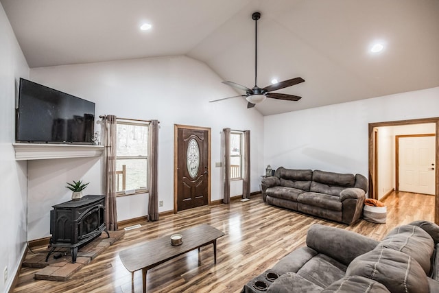 living room featuring ceiling fan, recessed lighting, wood finished floors, baseboards, and a wood stove