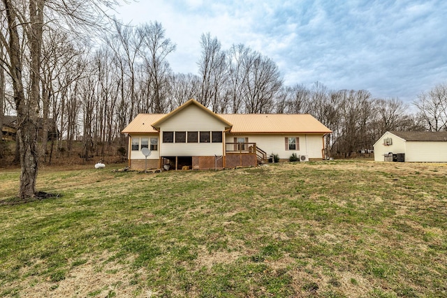 rear view of property featuring a sunroom, metal roof, and a lawn