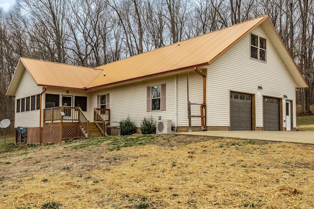 view of front of home with a garage, metal roof, driveway, and a sunroom