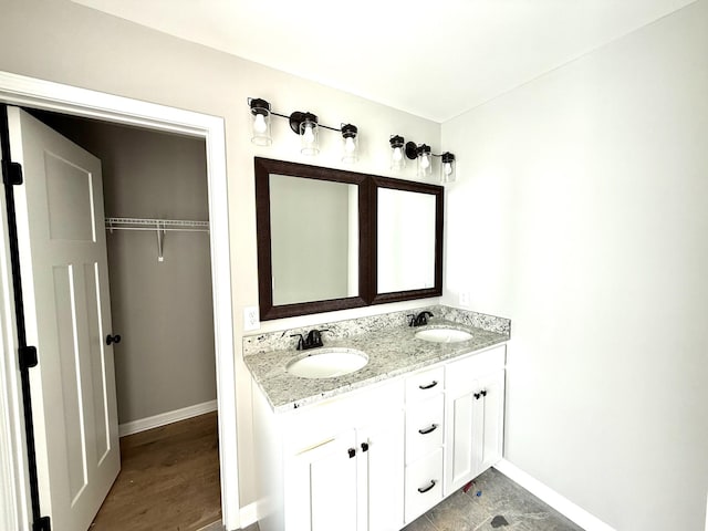 bathroom with a sink, baseboards, and double vanity