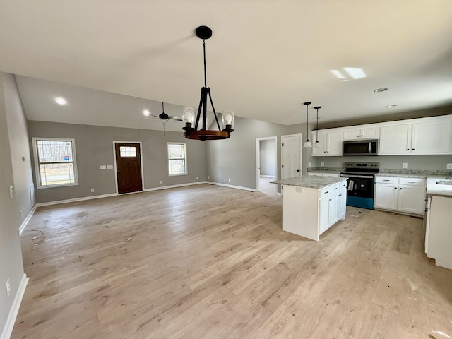 kitchen with stainless steel microwave, range with electric cooktop, vaulted ceiling, and a center island