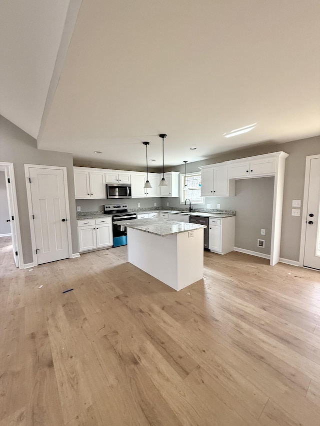 kitchen with appliances with stainless steel finishes, light wood-style floors, white cabinetry, and a kitchen island