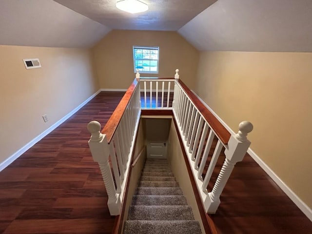 stairs with lofted ceiling, wood finished floors, visible vents, and baseboards