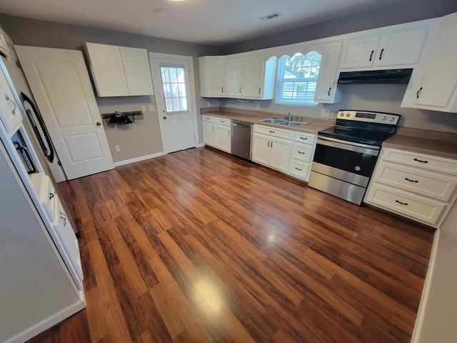 kitchen with under cabinet range hood, stainless steel appliances, dark wood-type flooring, a sink, and visible vents