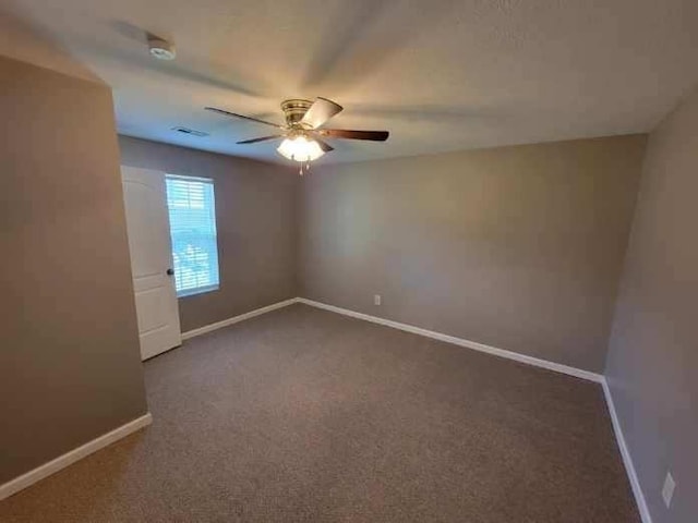 carpeted empty room featuring visible vents, ceiling fan, and baseboards