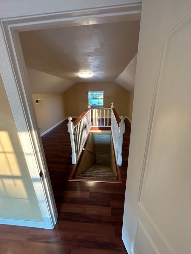 stairs with lofted ceiling, wood finished floors, and baseboards