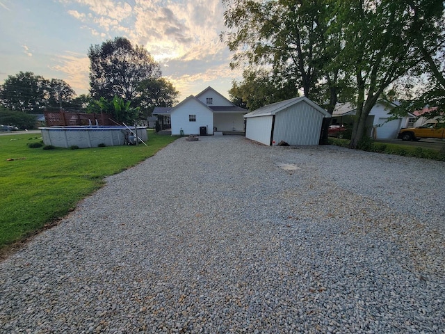 view of front of house featuring a fenced in pool, a front yard, gravel driveway, and an outdoor structure