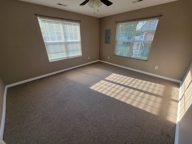 empty room featuring electric panel, carpet flooring, visible vents, and baseboards