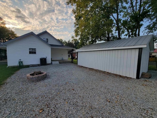 view of side of home featuring an outdoor fire pit, central AC, and an outbuilding