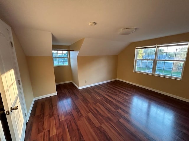 bonus room with dark wood-type flooring, lofted ceiling, and baseboards