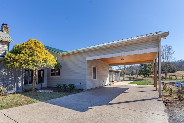 exterior space with metal roof, driveway, an attached carport, and fence