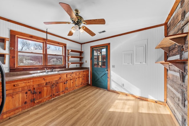 kitchen with open shelves, visible vents, ornamental molding, a sink, and light wood-type flooring