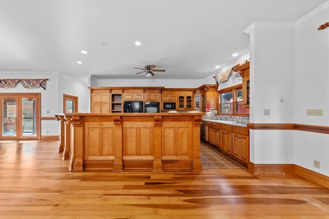 kitchen featuring a breakfast bar area, open shelves, a sink, light wood-type flooring, and black appliances