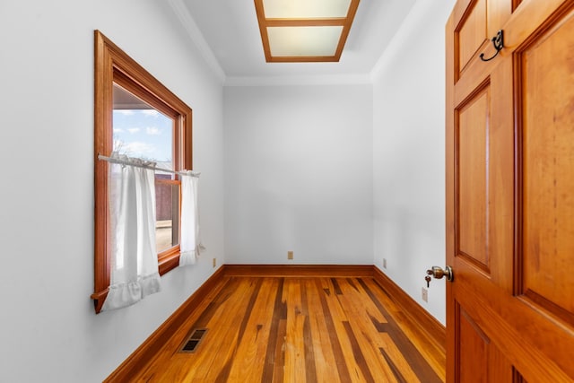 spare room featuring crown molding, hardwood / wood-style flooring, visible vents, and baseboards