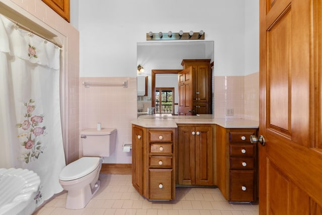 bathroom featuring a wainscoted wall, tile walls, toilet, vanity, and tile patterned flooring