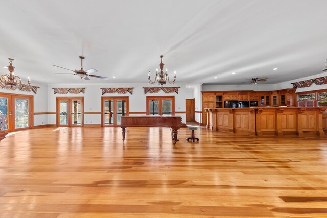 interior space with light wood-style floors, french doors, and ceiling fan with notable chandelier