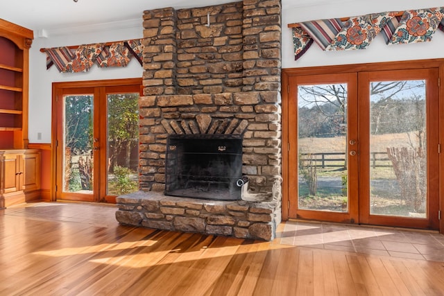 unfurnished living room with ornamental molding, french doors, wood-type flooring, and a wealth of natural light