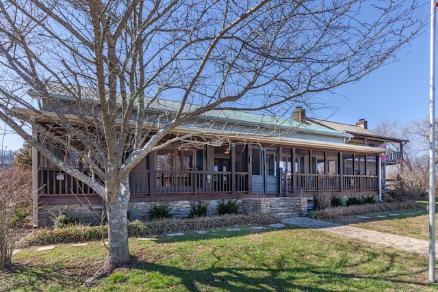 view of front of home with covered porch, a chimney, and a front lawn