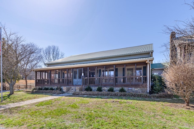 view of front of home with a sunroom, metal roof, and a front lawn