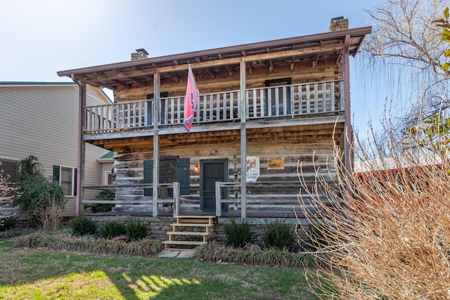 view of front of property featuring a chimney and a balcony