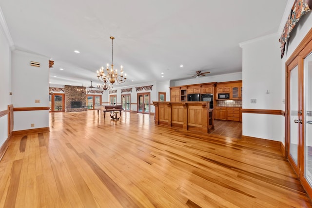 living room with ceiling fan with notable chandelier, ornamental molding, a fireplace, and light wood-style floors