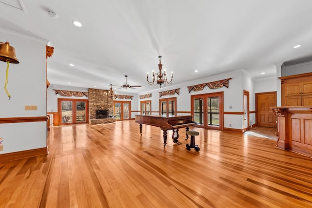 game room with light wood-style flooring, crown molding, a fireplace, french doors, and an inviting chandelier