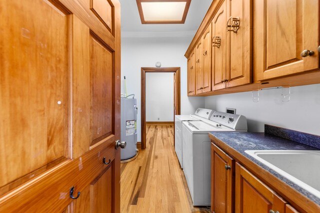 laundry room with cabinet space, independent washer and dryer, electric water heater, light wood-type flooring, and a sink