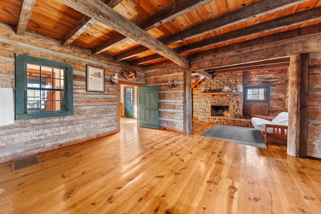 unfurnished living room with a stone fireplace, wooden ceiling, visible vents, beamed ceiling, and wood-type flooring