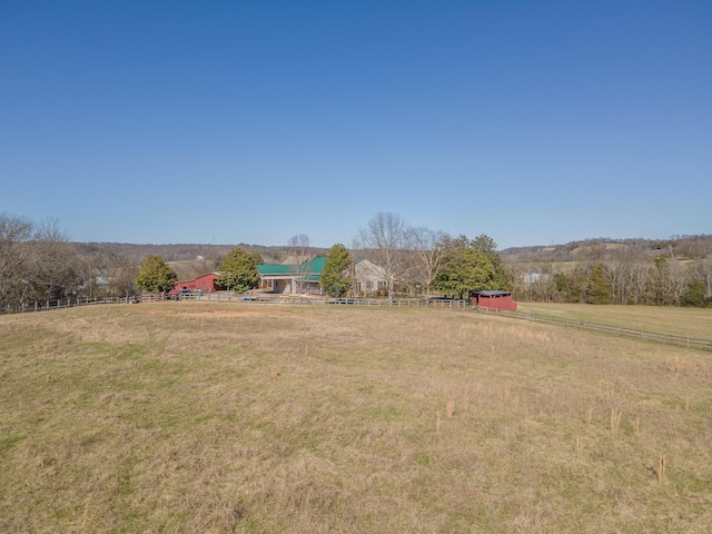 view of yard with fence and a rural view