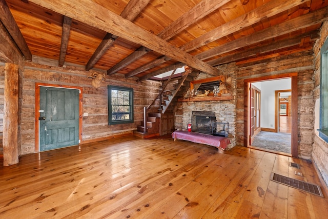 unfurnished living room with wooden ceiling, beamed ceiling, hardwood / wood-style floors, stairs, and a stone fireplace