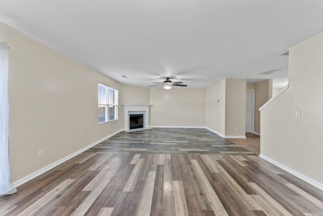 unfurnished living room featuring visible vents, a fireplace with flush hearth, a ceiling fan, wood finished floors, and baseboards